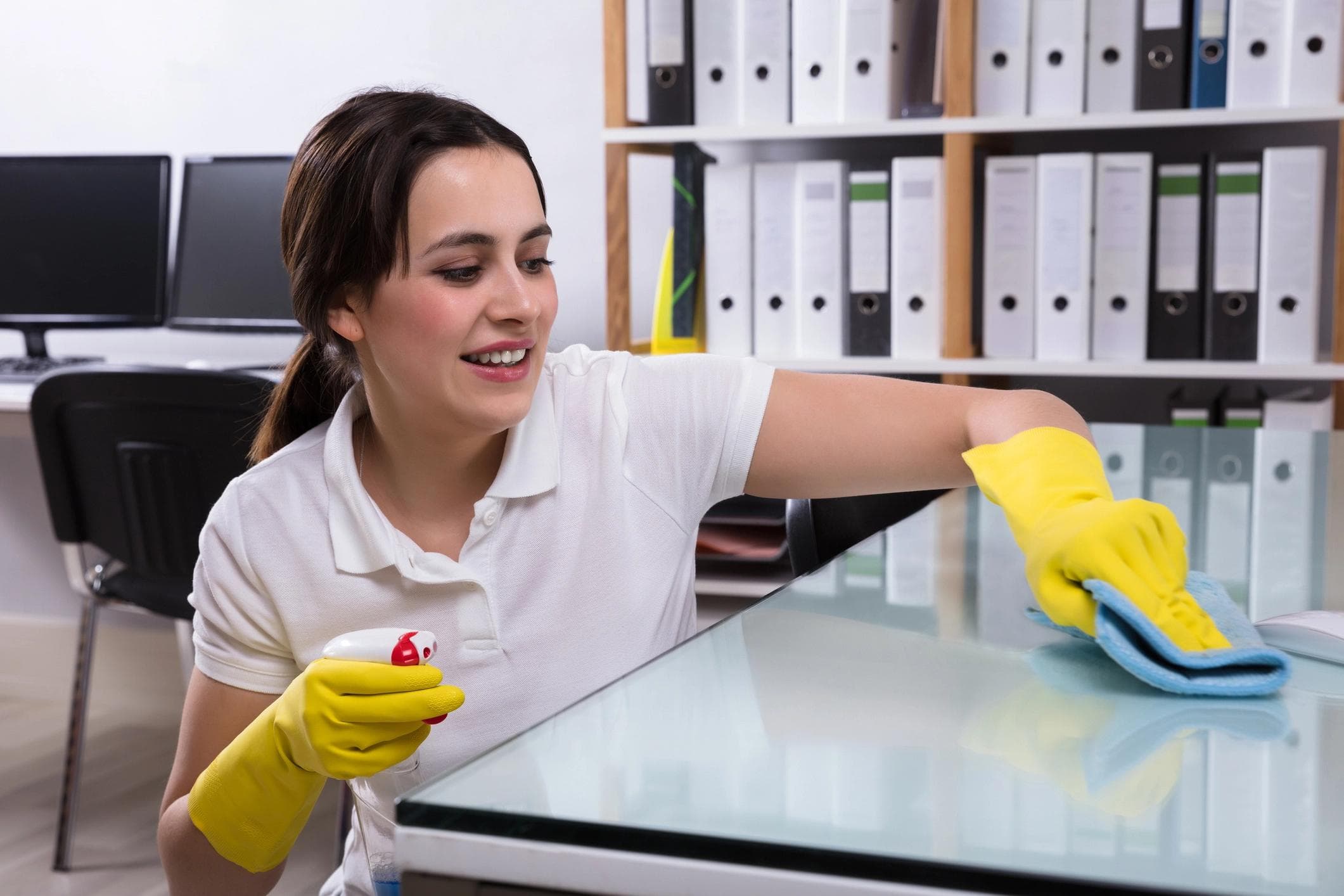 Employee carefully cleaning a glass desk.
